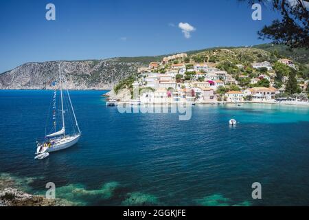 Barca a vela nella piccola baia di Assos graziosa cittadina sulla costa ionica, isola di Cefalonia, Grecia Foto Stock