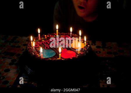 Ragazzo che soffia le candele sulla torta di compleanno al cioccolato - USA Foto Stock