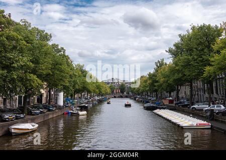 Amsterdam, Paesi Bassi - 13 agosto 2021: Keizersgracht se a riflessione chiara dal ponte di Leidsestraat con fogliame verde su entrambi i lati. Barche su w Foto Stock