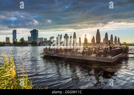 Vienna, sole tardivo al fiume Alte Donau (Vecchio Danubio), piattaforma galleggiante di ristorante Strandcafe, barche, torre Donauturm, altipiani di Donaucity, DC Towe Foto Stock