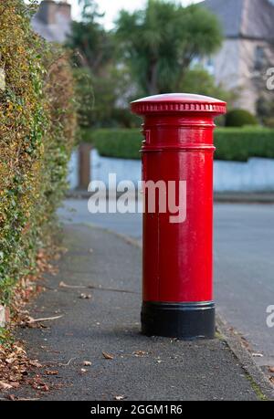 Un paletto rosso dell'ufficio postale della posta reale sul bordo del marciapiede a Ramsey, isola di Man Foto Stock