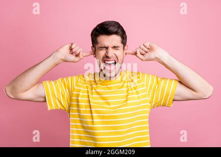 Ritratto di attraente arrabbiato disperato ragazzo yelling chiusura orecchie isolate su sfondo rosa pastello colore Foto Stock