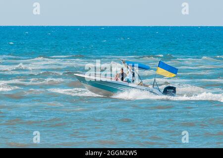 Ucraina, Porto di ferro - 24 agosto 2020: Un popolo ucraino in barca o nave vela attraverso il mare con bandiera di simboli ucraini. Foto Stock