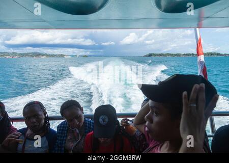 Sorong, Indonesia - 3 ottobre 2019: In lontananza, dietro la scia della nave è Sorong, in primo piano, le donne papuane si recano a Waisai Foto Stock