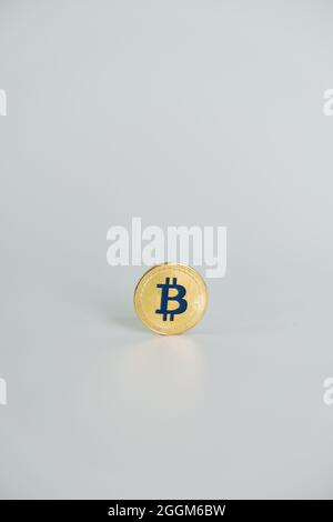 Una moneta di colore oro Bitcoin con la lettera 'B' di colore blu, centrata su sfondo grigio chiaro. Bitcoin - BTC bit Coin - Crypto valuta. Foto Stock