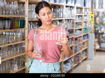 Donna che acquista vetreria in negozio di casa Foto Stock