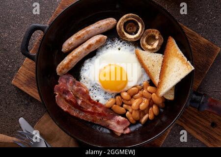 Prima colazione inglese classica in padella con uova, prosciutto, fagioli, funghi, salsicce e toast Foto Stock