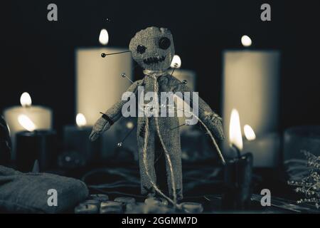 Concetto di Voodoo Magic. Bambola Voodoo costellata di aghi con cuore di straccio trafitto sul pentagramma e intorno a candele brucianti. Rituale esoterico magico o inquietante, foto in bianco e nero. Foto Stock