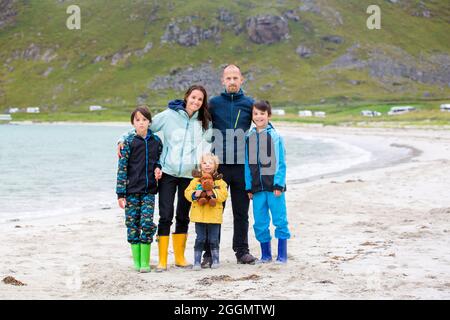 Famiglia felice, godendo le spiagge di sabbia bianca a Lofoten, Norvegia in una fredda giornata di pioggia estate, concetto felice di famiglia Foto Stock