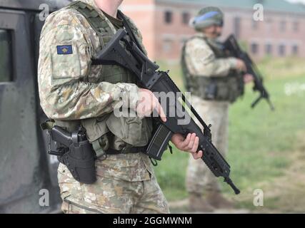 Soldati con fucile d'assalto e bandiera del Kosovo su uniforme militare. Collage. Foto Stock