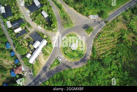 Vista aerea della strada rotonda in un villaggio circondato da alberi in campagna Foto Stock