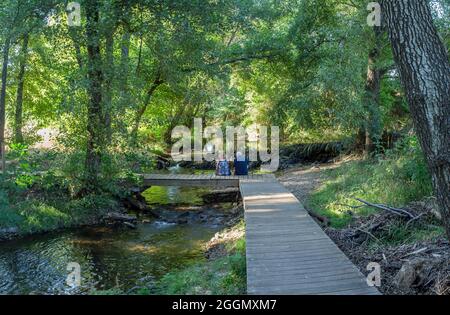 Fiume Gevora, la Codosera, Badajoz, Estremadura, Spagna. Coppia anziana seduta su ponte di legno Foto Stock