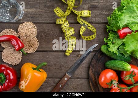 Bicchiere d'acqua con verdure e nastro di misurazione sul tavolo primo piano Foto Stock