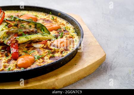 Primo piano con uova al peperone e zucchine cotte in forno in padella in ghisa Foto Stock