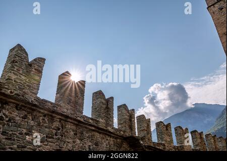 Il sole filtra attraverso i merli del Castello di Fenis, Valle d'Aosta, Italia, nelle prime ore del nuovo giorno Foto Stock