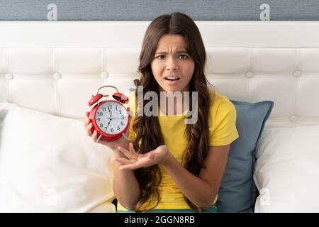 La ragazza infelice si lamenta della sveglia a letto, ora del mattino Foto Stock