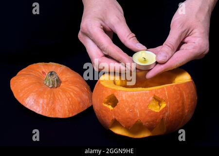 Passo 4 mettere una candela illuminata nella zucca scolpita per preparare la lanterna di Jack, isolato su sfondo nero, primo piano, spazio copia. Istruzioni dettagliate Foto Stock