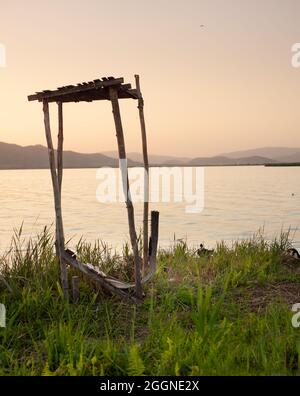 Piccolo Lodge in legno tra molti querce accanto ad un lago Foto Stock