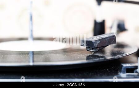 l'ago di un giradischi che riproduce le tracce di un disco in vinile nero. Impianto audio vintage. Lettore di dischi in vinile Foto Stock