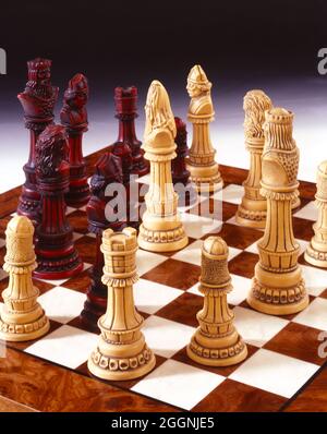 pezzi di scacchi scolpiti su tavola di legno graduato sfondo grigio spazio copia Foto Stock