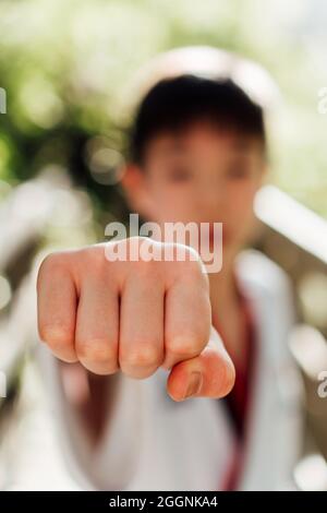 Ritratto di un giovane giocatore giapponese di karate in posizione di attacco o difesa vestito con il suo tae kwon ufficiale do kimono. Pugni forti e aggrappati per il combattimento Foto Stock