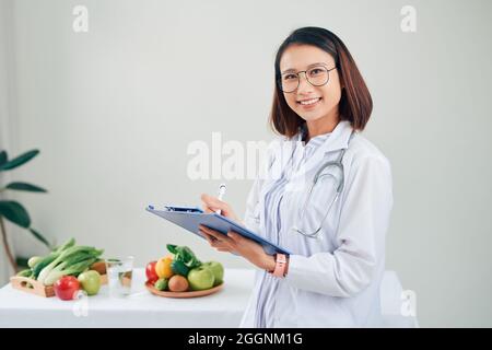 Nutrizionista femmina con frutti lavorando alla sua scrivania Foto Stock