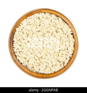 Tofu bianco sbriciolato, in una ciotola di legno. Schiacciare la cagliata di fagioli, il latte di soia coagulato, pressato in blocchi bianchi di diversa morbidezza. Foto Stock