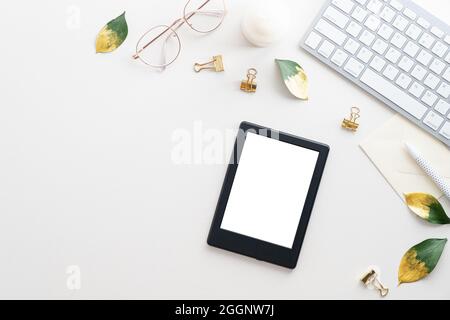 E-book tablet mockup, tastiera, occhiali su scrivania bianca. Disposizione piatta, vista dall'alto, spazio di copia. Comodo tavolo da ufficio, elegante spazio di lavoro femminile. Foto Stock