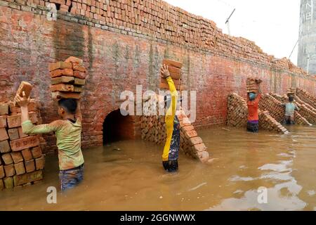 Munshiganj City, Bangladesh. 01 Settembre 2021. MUNSHIGANJ CITY, BANGLADESH- 1 SETTEMBRE: Un migrante del Bangladesh tiene blocchi di mattoni sopra la sua testa per trasportarla sull'altro lato del fiume ad un mattone-campo in Dhaka. Circa 400,000 migranti a basso reddito arrivano a Dhaka ogni anno per lavorare a brickfields, nella fabbrica di mattoni milioni di mattoni vengono bruciati anche se questo influisce sull'ambiente in Bangladesh. Il 1 settembre 2021 a Munshiganj City, Bangladesh. (Foto di Harun-or-Rashid/Eyepix Group) (Foto di Eyepix/Sipa USA) Credit: Sipa USA/Alamy Live News Foto Stock