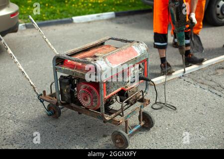 Generatore di benzina di elettricità. Alimentazione all'utensile elettrico. Generatore sulla strada per la riparazione stradale. Foto Stock