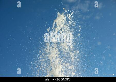 Spruzzi d'acqua nell'aria. Un jet di fantasia sullo sfondo del cielo. Piccole gocce volano ai lati. Foto Stock