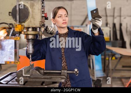 Craftswoman che lavora su una macchina per la perforazione di strutture metalliche Foto Stock