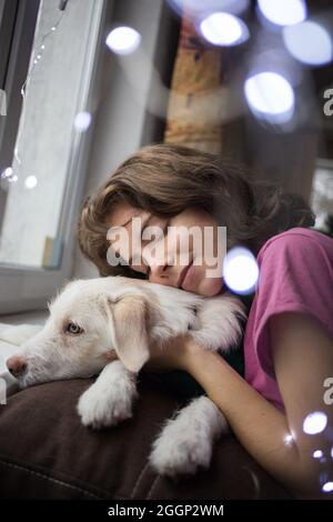 ritratto di una ragazza adolescente carina abbracciando il suo amato cane bianco. amicizia tra una ragazza e un animale domestico. Sogni la vigilia di Natale, in previsione dell'inverno Foto Stock