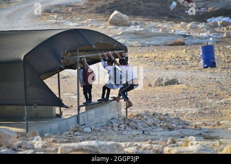 Dal 2004 i bambini del villaggio di Tuba stanno andando a scuola nel vicino villaggio di AT-Tuwani, 2.6 km di distanza - mentre sono stati condotti da un attivista ebraico e un veicolo delle forze di difesa israeliane per proteggerli dagli attacchi violenti da parte dei coloni ebrei religiosi dall'avamposto illegale di Maon Farm, che si trova sul loro cammino verso la scuola. Palestina/Israele, a sud di Hebron. 31 agosto 2021. (Foto di Matan Golan/Sipa USA) Credit: Sipa USA/Alamy Live News Foto Stock