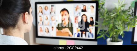 Donna che comunica con il gruppo di persone aziendali tramite videoconferenza Foto Stock