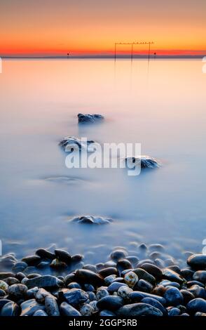 Blick von Arbon über den Bodensee bei Sonnenaufgang mit Steinen im Vordergrund Foto Stock