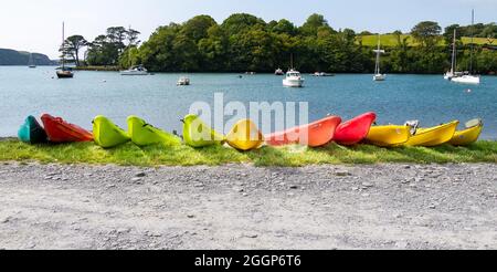 Archi in kayak colorati allineati sul bordo delle acque Foto Stock