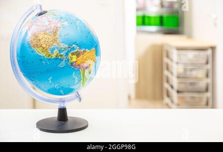 Globe School Planet Earth sulla scrivania degli studenti, sfondo interno camera sfocata. Educazione, cartografia, paesi e mappa politica mondiale, ritorno a scuola co Foto Stock