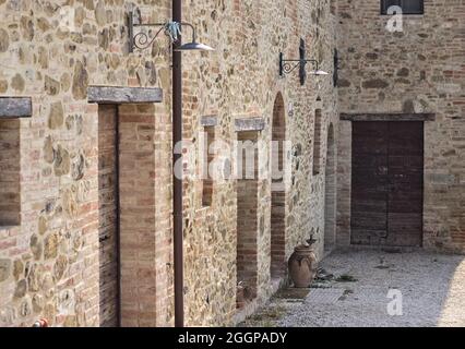 La facciata di un casale rurale in pietra con porte e finestre in legno nella campagna italiana (Toscana, Italia, Europa) Foto Stock