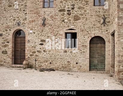 La facciata di un casale rurale in pietra con porte e finestre in legno nella campagna italiana (Toscana, Italia, Europa) Foto Stock