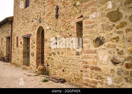 La facciata di un casale rurale in pietra con porte e finestre in legno nella campagna italiana (Toscana, Italia, Europa) Foto Stock