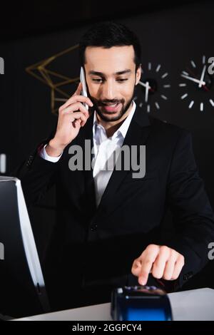 un'allegra receptionist che parla sullo smartphone dell'hotel Foto Stock