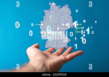 Primo piano di una mappa di rendering 3D della Germania con cifre binarie sulla mano di un uomo Foto Stock