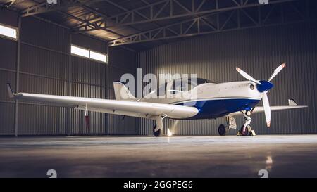 Piccolo jet privato bianco parcheggiato nell'hangar Foto Stock