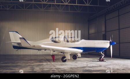 Piccolo jet privato bianco parcheggiato nell'hangar Foto Stock