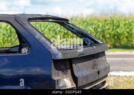 La parte posteriore di un'auto da passeggeri bruciata. Ci sono resti di schiuma a terra, che i vigili del fuoco usavano per spegnere l'incendio. Foto Stock