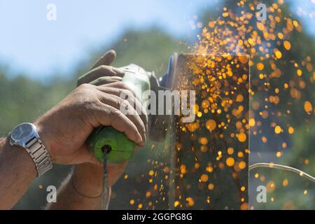 l'uomo utilizza una flessibilità che produce scintille senza l'uso di guanti protettivi. Mancanza di utilizzo dei sistemi di protezione e imprudenza sul lavoro Foto Stock