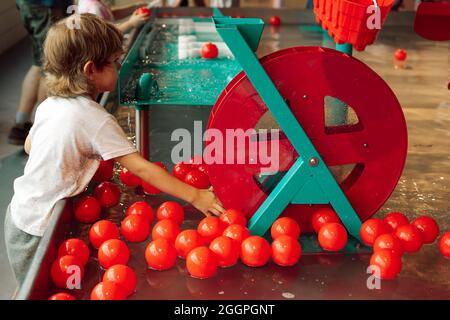 Attrezzature e palle d'acqua luminosa hanno catturato completamente l'attenzione del fboy nel centro di intrattenimento per bambini. Centro ricreativo per bambini. SENS tattili Foto Stock