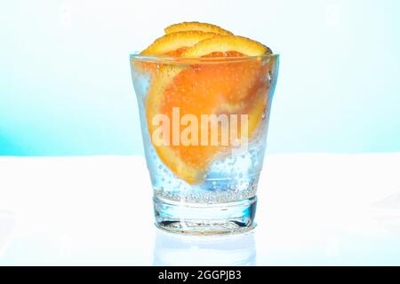 fette d'arancia con bolle in un bicchiere di acqua frizzante appannato Foto Stock