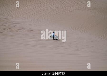 Vista pittoresca di guida ATV nel deserto e piste di pneumatici sulla sabbia durante la giornata di sole durante le vacanze estive. Due persone che guidano ATV in dune di sabbia bianca Foto Stock